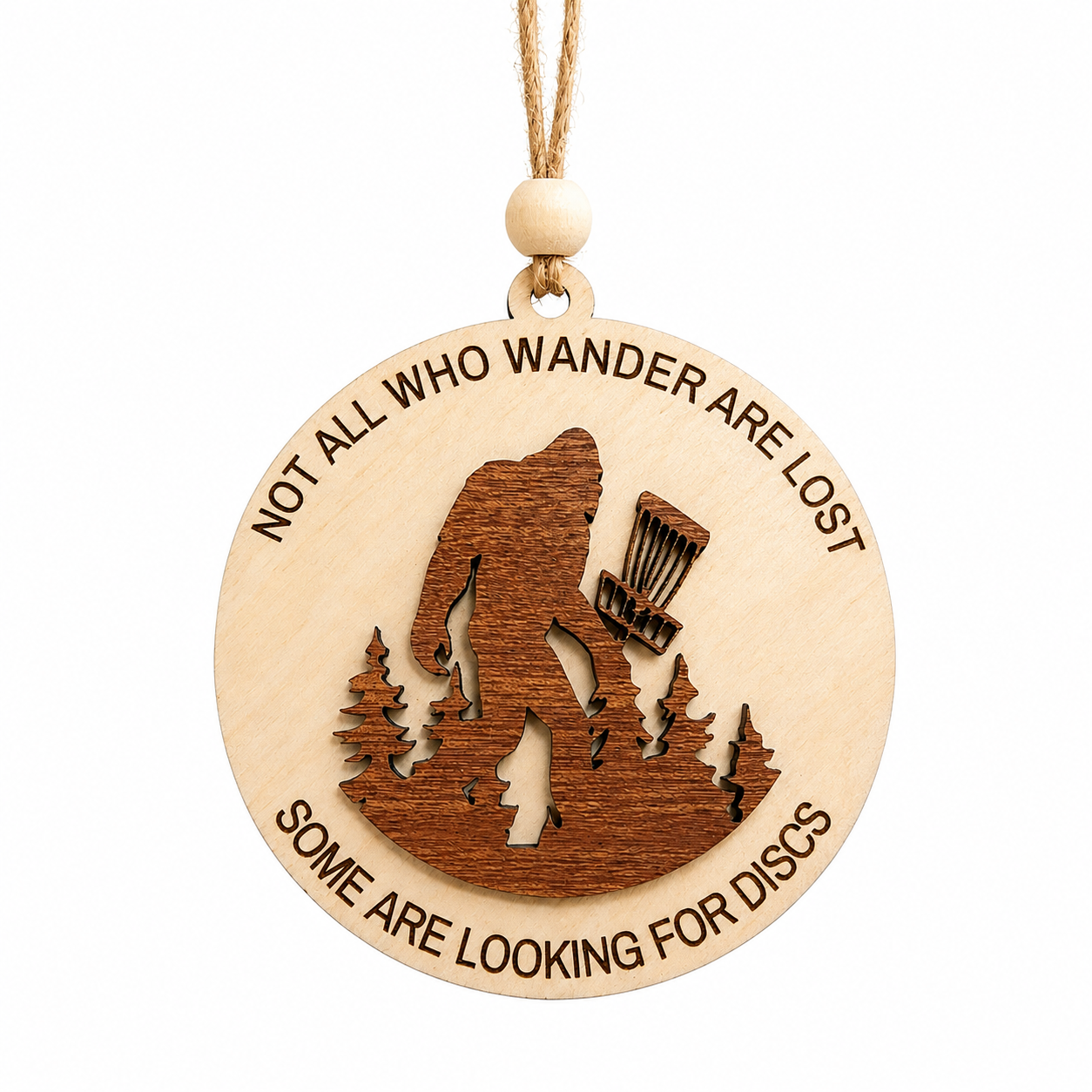 Layered laser-cut wood Bigfoot disc golf ornament displayed on a white background with engraved woodland design.