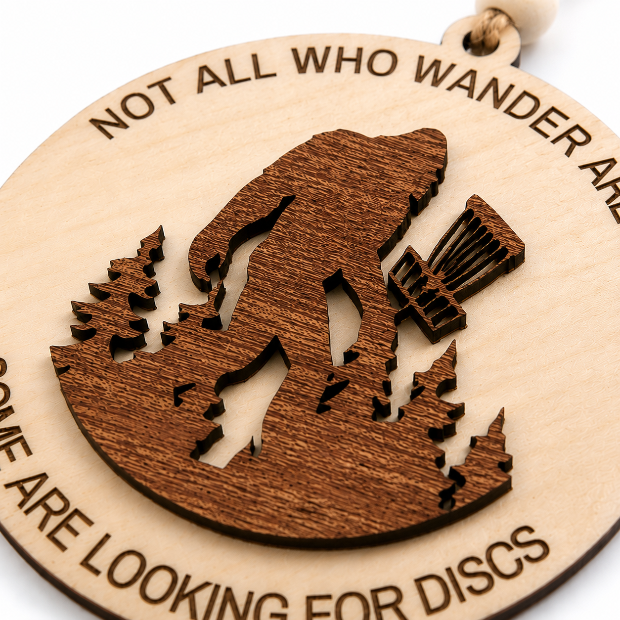Close-up of the engraved Bigfoot disc golf ornament showing layered wood details and natural grain.