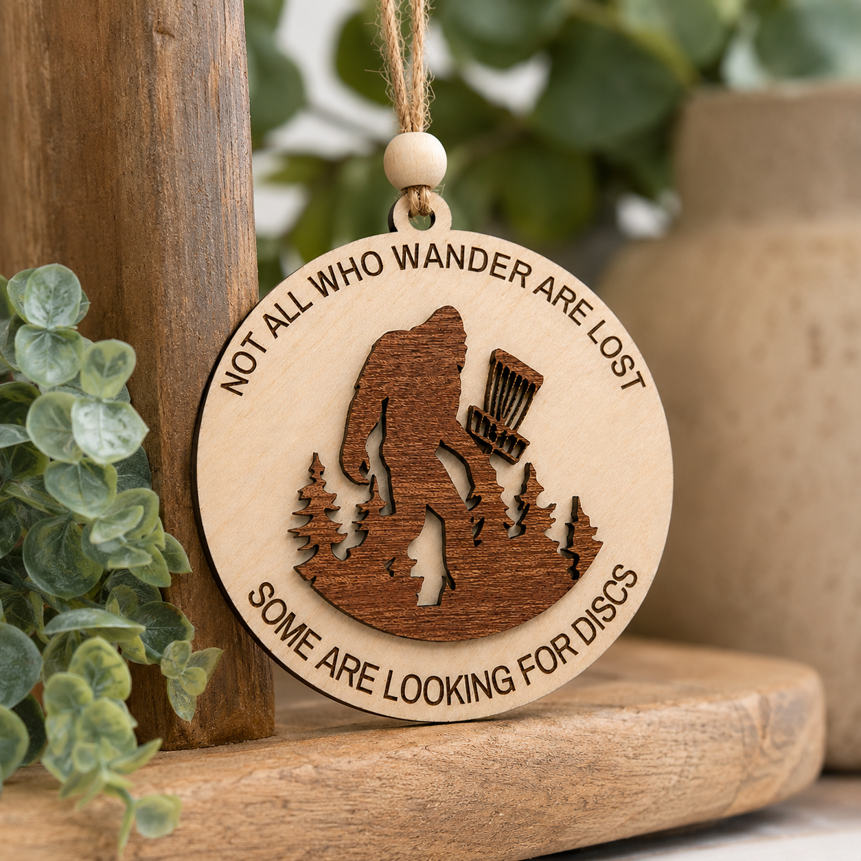 Handmade Bigfoot disc golf ornament displayed in a cozy woodland-inspired Christmas setting.
