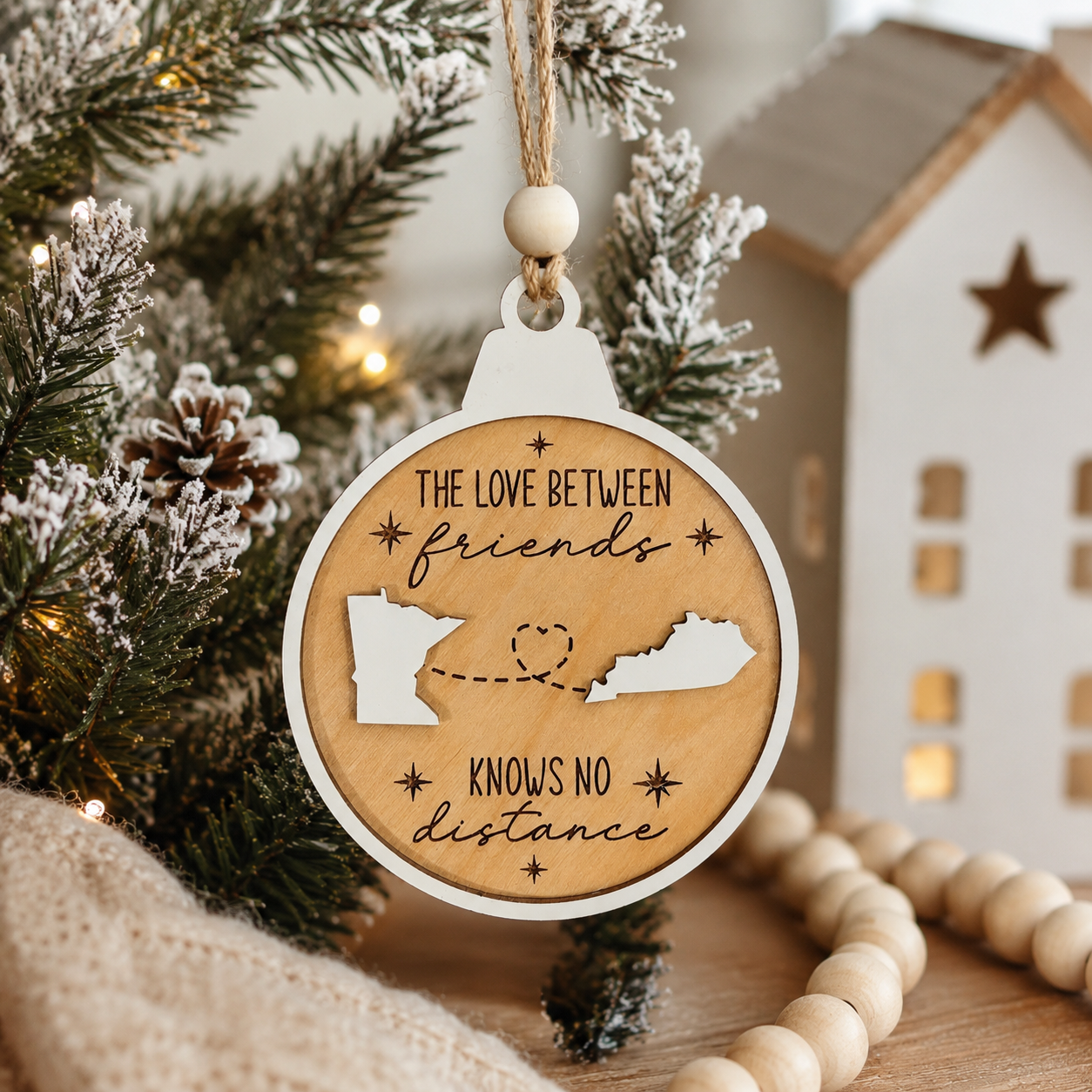 Personalized long distance Christmas ornament hanging on a decorated Christmas tree with custom state silhouettes and friendship message.