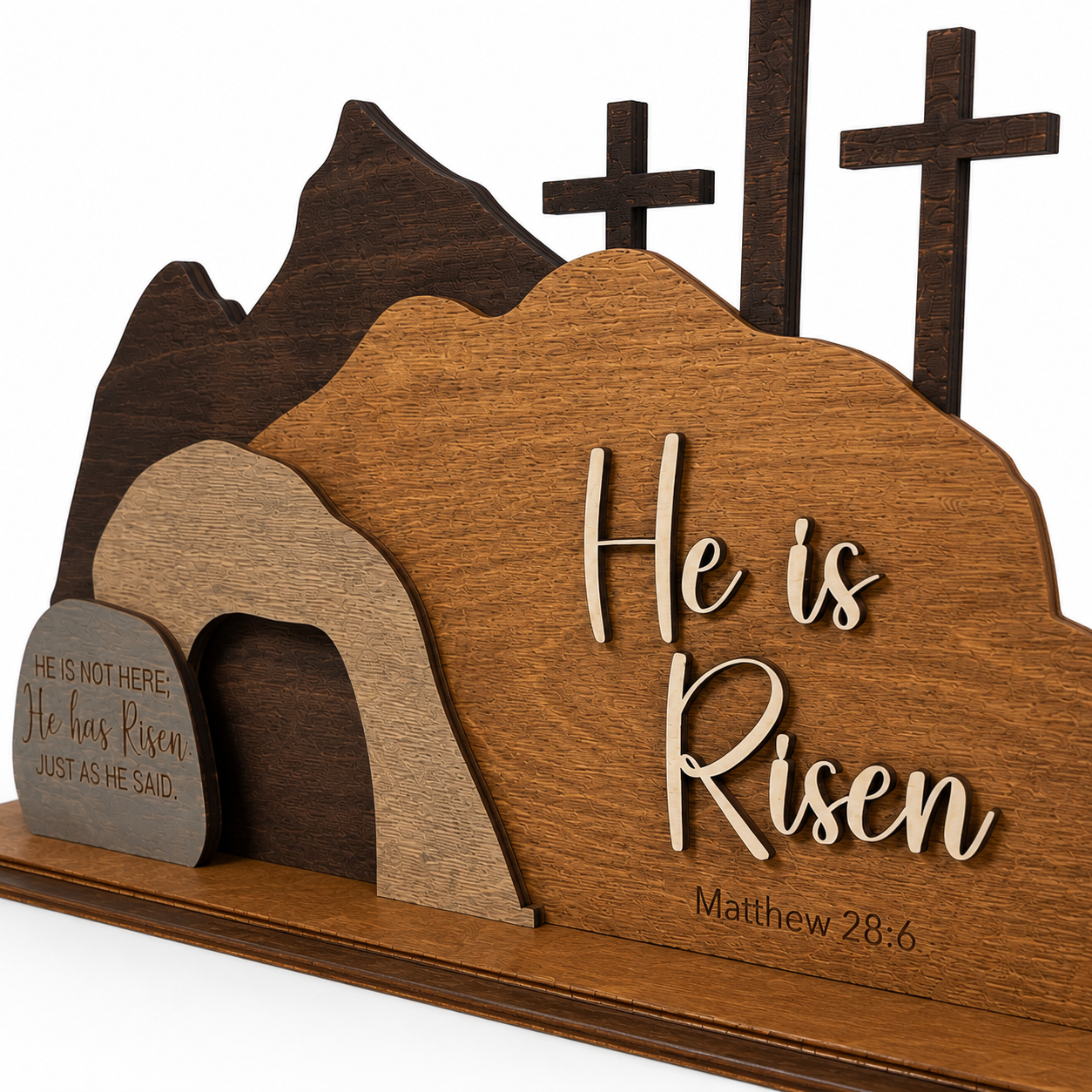 Close-up detail of the He Is Risen wooden resurrection scene highlighting the empty tomb, layered wood craftsmanship, engraved Matthew 28:6, and natural wood grain.