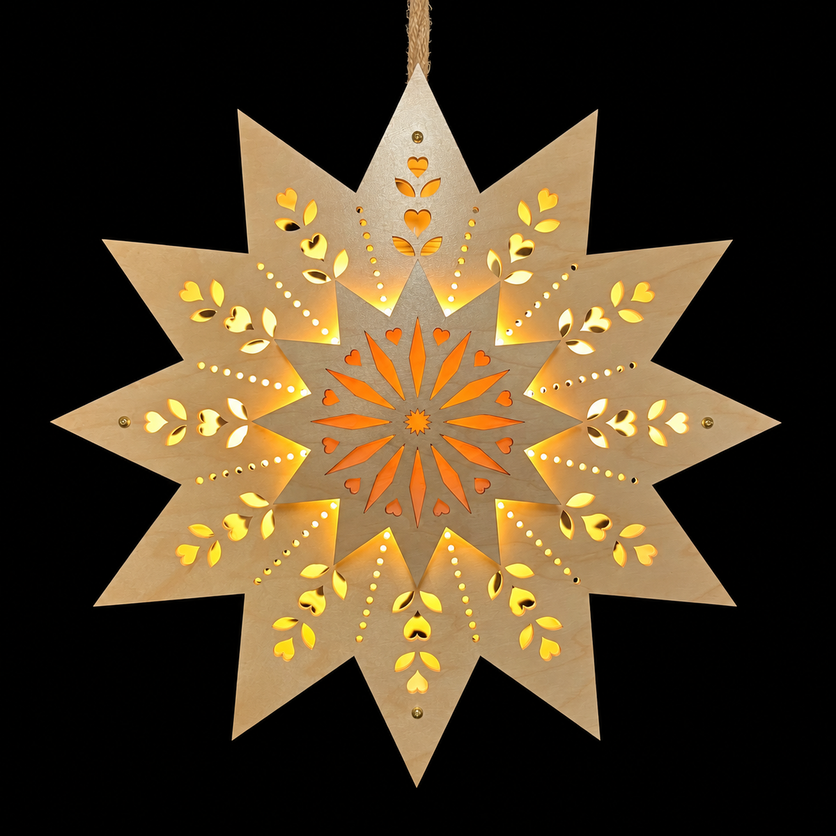Front view of an illuminated maple wooden Welcome Light with a raised starburst center and warm light glowing through decorative heart and leaf cutouts.